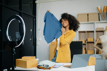 Beautiful lady blogger showing clothes in front of the camera to recording vlog video live...