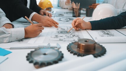 Close-up of hands tracing over technical drawings and mechanical designs during an engineering...