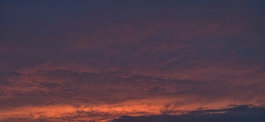 Fototapeta premium Colorful sky with clouds at sunset or sunrise with orange and purple hues.