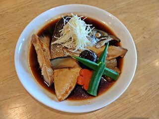 Salmon Kabutoni or salmon head with sweet sauce in white plate on wooden table. Japanese food.