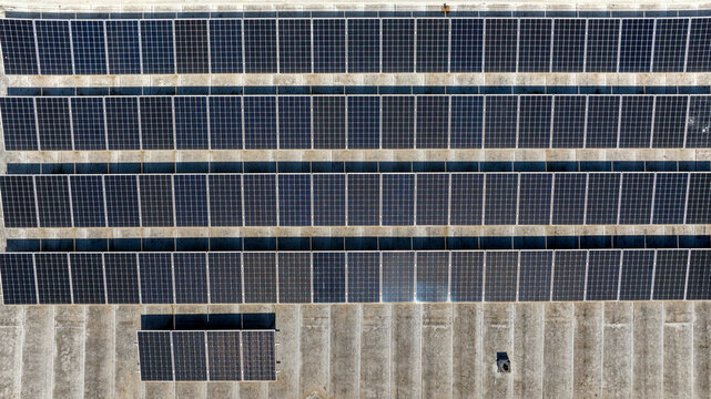 Aerial perpendicular view of rows of solar panels installed on the roof of a building. Clean energy concept.