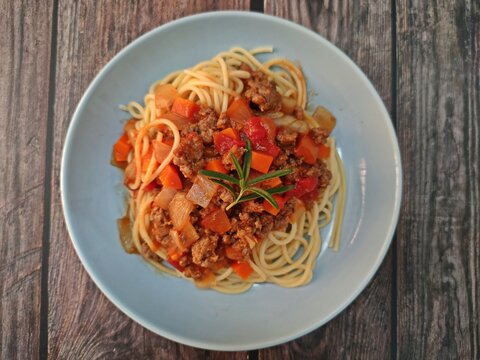 Spaghetti ground beef sauce served in a plate on wooden table.