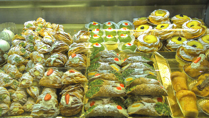 Display of Italian pastries with cannoli and sfogliatella in a bakery window.