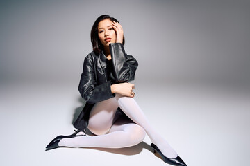 Young stylish woman posing elegantly in a chic black outfit against a minimalistic backdrop