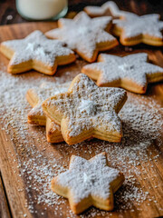 Cookies dusted with powdered sugar on parchment paper, surrounded by star-shaped cookie cutters on a wooden table.