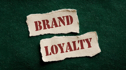 Torn beige paper pieces on dark-green background display words "Brand" and "Loyalty", symbolizing brand building and customer relationship