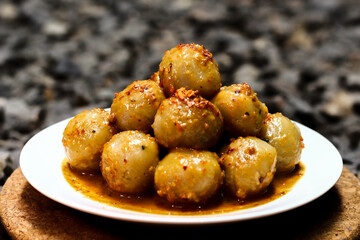 Cilok is a traditional food from Indonesia, made from tapioca, round shape, chewy textured. White plate on the gray gravel. Selective focus