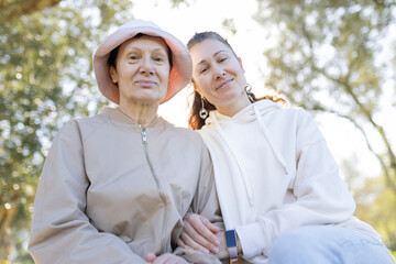 Senior woman with pink hat and her daughter enjoying sunny day in park