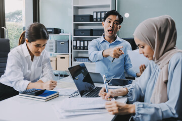 Young asian businesswoman suffering from headache while colleagues arguing and blaming her for bad work results during stressful office meeting