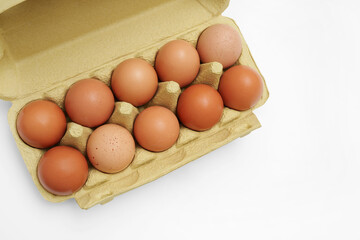 Top view of raw rustic brown eggs in a green paper box. Space for text.