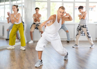 Obraz premium Young male teacher dancing hip hop dance with group of teenagers in studio