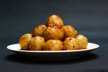 Cilok is a typical West Javanese food, made from tapioca flour and served with chilli sauce. It has a round shape like meatballs, isolated on a black background. Selective focus