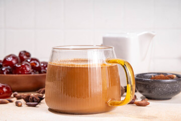 Healthy organic date seed coffee, coffee latte cup, made with grated date seeds, with whole date fruits and seeds on beige background . Alternative coffee hot drink