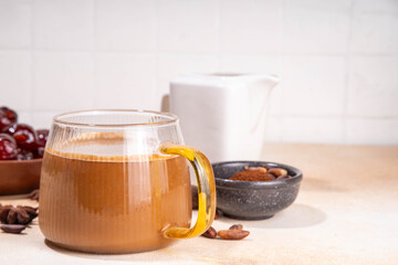 Healthy organic date seed coffee, coffee latte cup, made with grated date seeds, with whole date fruits and seeds on beige background . Alternative coffee hot drink