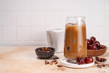 Healthy organic date seed coffee, iced coffee latte cup, made with grated date seeds, with whole date fruits and seeds on beige background . Alternative coffee hot drink