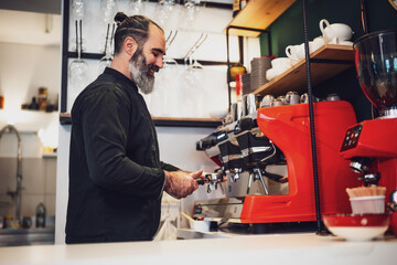 Professional barista in black apron working in restaurant. Portrait of happy barmen who is making coffee in his bar.