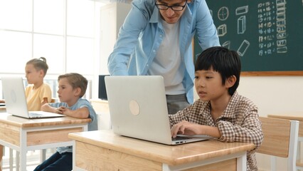 Caucasian teacher helping asian student coding engineering prompt while diverse student using...