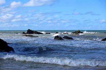 Blue sea with waves breaking near the sand of Coqueiros beach in the Joao Pessoa region, Northeast of Brazil. Sunny day with shadows and light over the water.