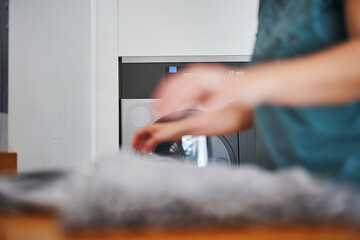 Blurred person folding laundry in front of dryer at laundromat