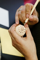 Woman hands painting Easter eggs with black bee wax, traditional Lithuanian method