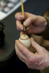 Woman hands painting Easter eggs with black bee wax, traditional Lithuanian method