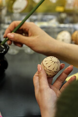 Woman hands painting Easter eggs with black bee wax, traditional Lithuanian method