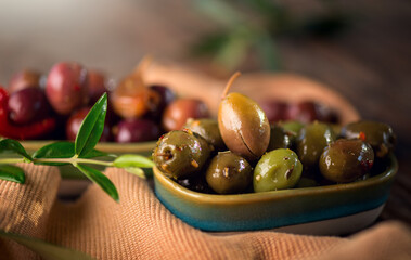 Olives, homemade marinated colorful olives with herbs and spices on rustic table, close up. Healthy Mediterranean vegan food, olive oil  
