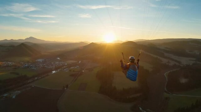 Soaring high above the rural landscape at golden hour in an epic paragliding journey, warm glow of sunset skies
