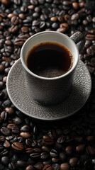 Fototapeta premium Grey ceramic coffee cup filled with dark coffee, rests on a saucer amidst numerous coffee beans, showcasing a rich, dark beverage concept