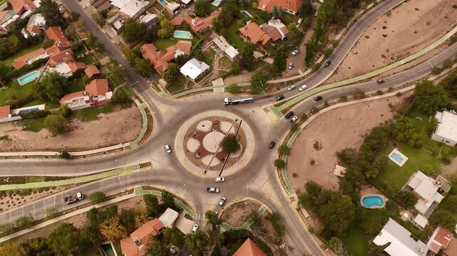 Aerial top down of traffic scene on roundabout in Lujan de Cuyo Area, Mendoza during Sunset time. Fancy neighborhood With houses and Swimming pool.