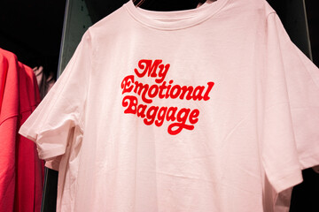 My emotional baggage. White T-shirt with bold red text on display in a clothing store