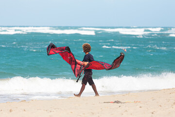 Kitesurfing. Professional kiter walks along the beach with his kite. Kitesurfing Kiteboarding photos