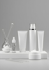 White skincare products with laboratory glassware on gray background