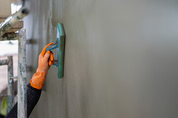 Professional contractor plastering wall with sponge float to make a smooth rendering.