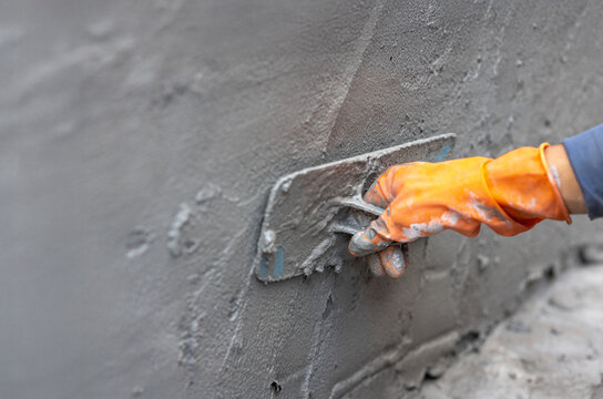 Worker applying cement on wall in construction site.