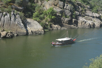 Scenic boat tour along a river surrounded by rocky cliffs during a sunny day in a natural landscape setting