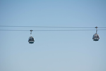 Cable cars glide through clear skies above a scenic landscape during a bright sunny day