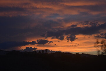 Beautiful sunset with vibrant colors and silhouette of buildings against the horizon in a tranquil evening sky