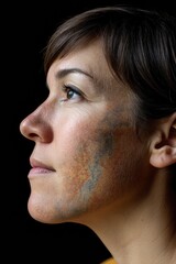 Side profile of woman with painted facial detail looking into distance under black background portraying individuality introspection and abstract facial ornamentation in fine art photography style