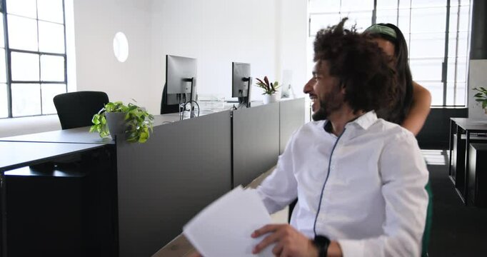 Happy businesswoman pushing businessman in office chair in office and scattering papers