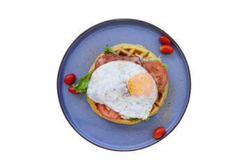 Fresh waffles with fried eggs, lettuce, tomatoes and served for breakfast on a white background.