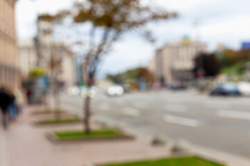 Blurred background of city boulevard with buildings, trees and cars in motion. Concept of modern city life. Blurred background of city street with trees and buildings