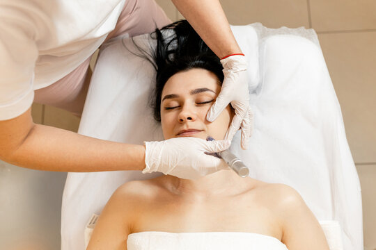 Cosmetologist doing microneedling, patient care using dermapen in a beauty salon
