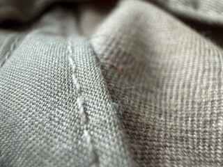 Close up of fabric texture highlighting stitching and fibers in neutral tones demonstrating...