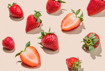 Fresh ripe strawberries scattered on beige background with natural sunlight.