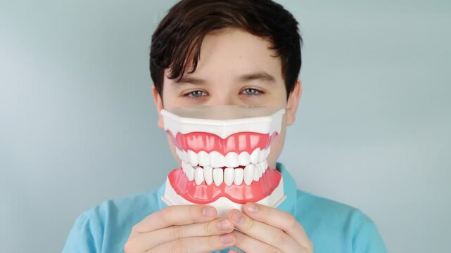 Smiling playful boy demonstrates large denture model with detailed tooth structure