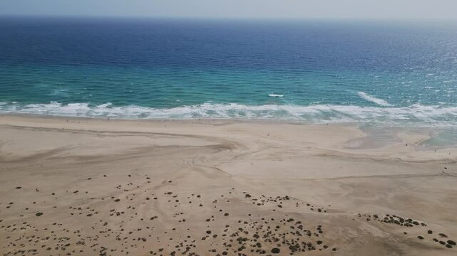 Aerial footage of Sotavento Beach in Fuerteventura under calima haze. Golden sand, calm sea, and soft desert tones &mdash; ideal for travel, nature, and climate visuals.