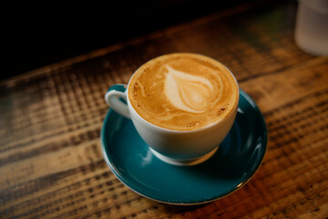 Cup of cappuccino with latte art on wooden table in cafe