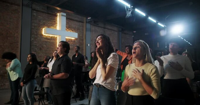 People worshiping together in church, raising hands in prayer, illuminated cross in background, joyful expressions, Christian faith and devotion
