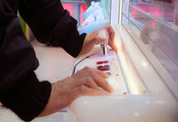 Playing a toy crawler crane machine joystick at arcade mall. © Tavan